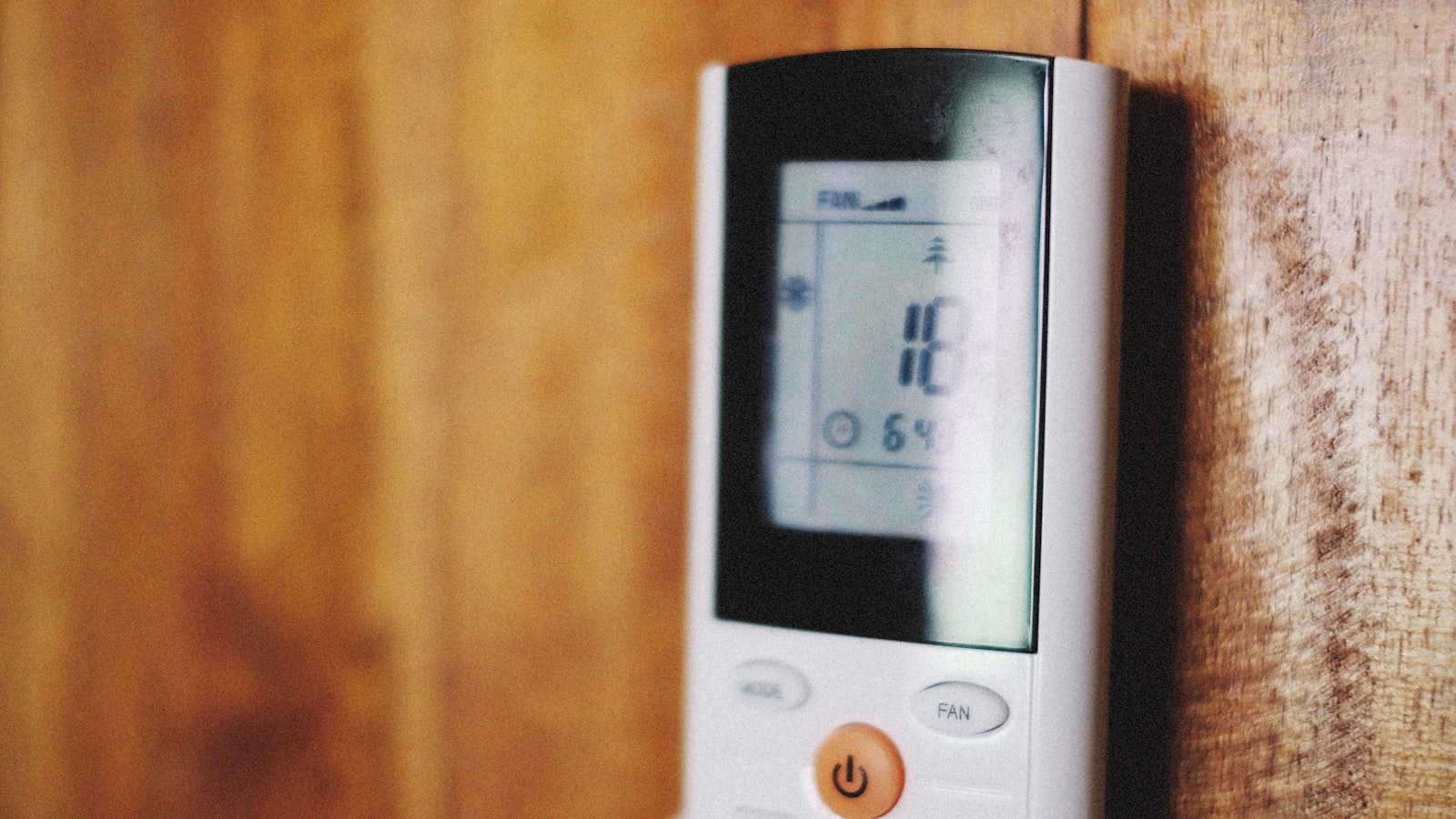 Main reglant la temperature d'un climatiseur sur la telecommande pendant la canicule
