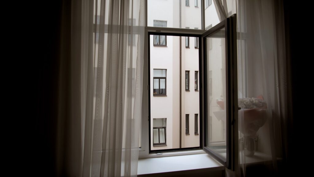 Rideaux thermiques et film solaire sur une fenêtre d'appartement exposée au soleil