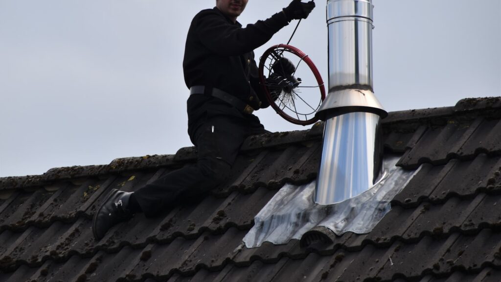 Professionnel intervenant sur un conduit de fumée dans la chaufferie d'une maison individuelle