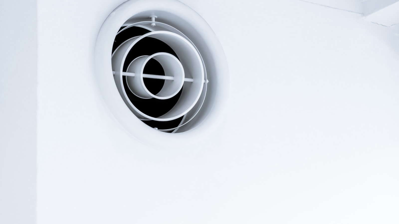 Bouche de soufflage circulaire de climatisation gainable dans un plafond blanc