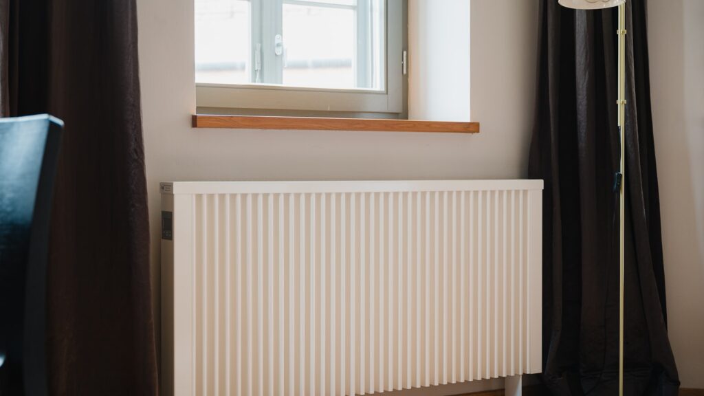 Radiateur a eau blanc pose sous une fenetre dans une piece de vie