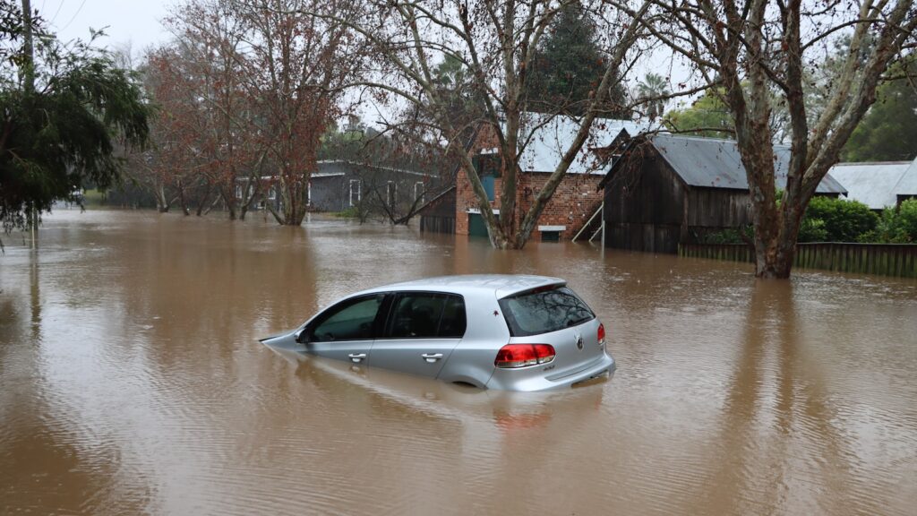 Rue residentielle inondee avec une voiture immergee apres une crue