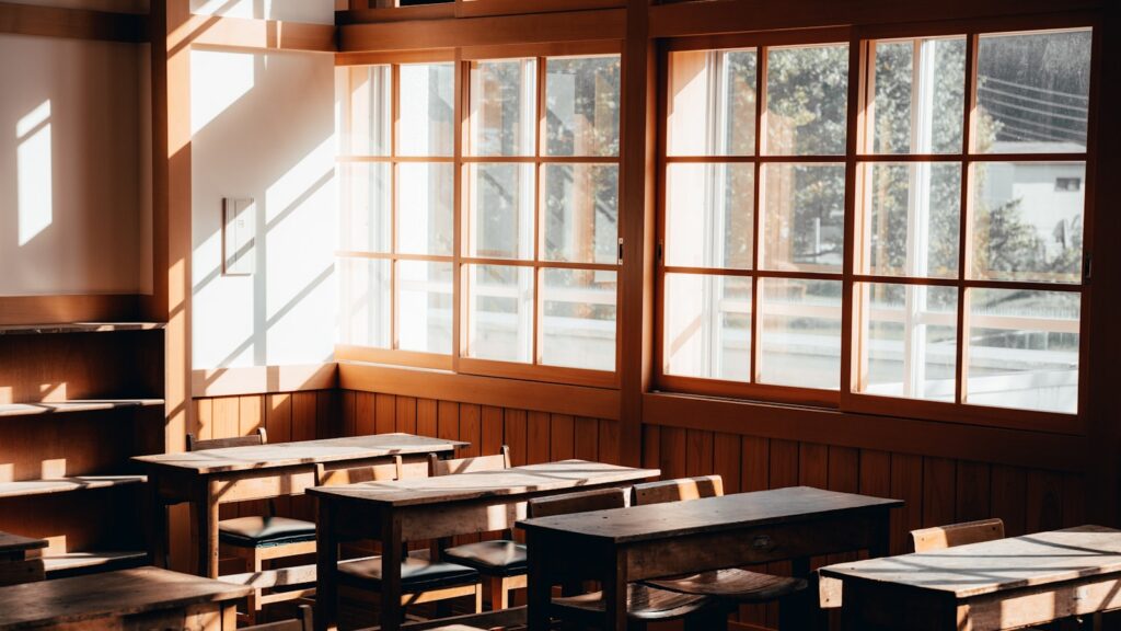 Salle de classe d'école primaire vide avec grandes fenêtres exposées au soleil