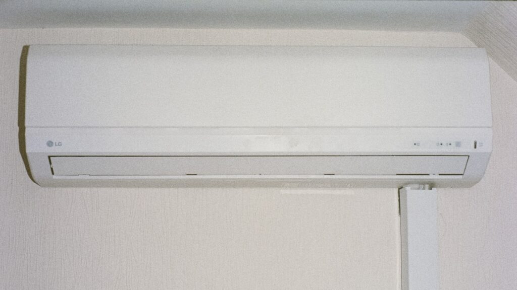 Tuyau d'évacuation des condensats sortant en façade sous une unité de climatisation