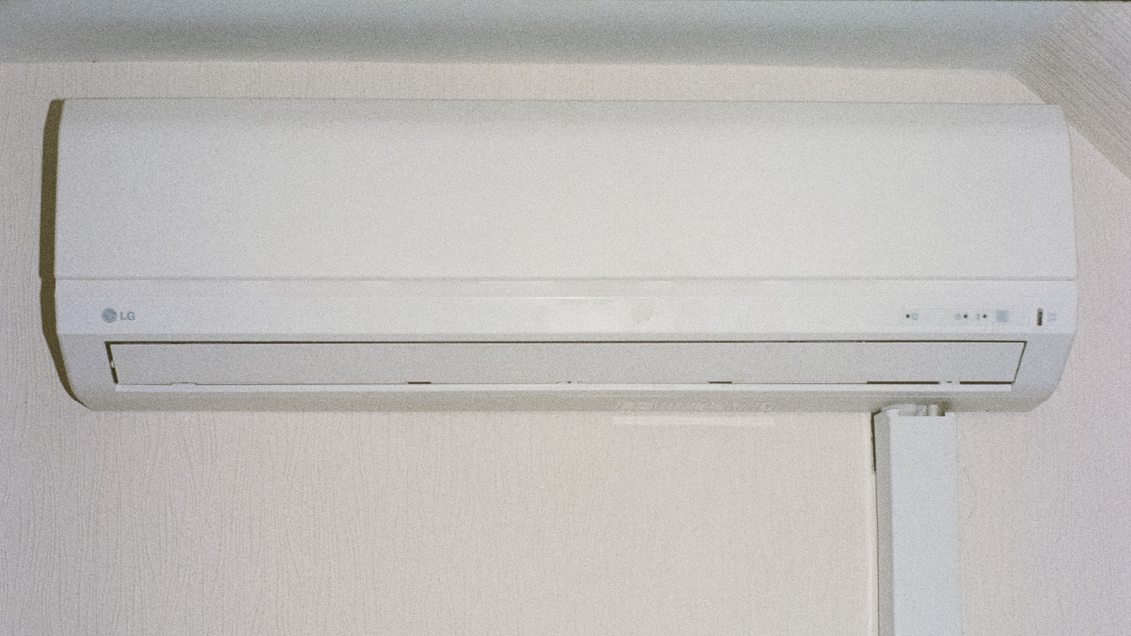 Tuyau d'évacuation des condensats sortant en façade sous une unité de climatisation