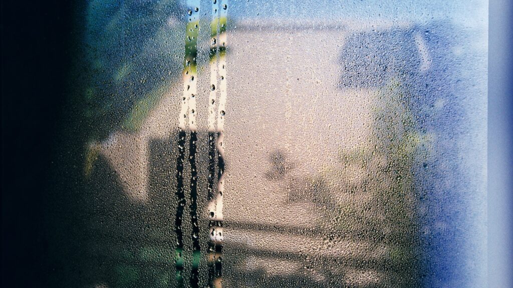 Condensation et ruissellement sur la vitre d'une fenêtre, signe d'un air humide au contact d'une paroi froide