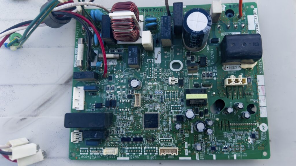 Technicien remplaçant une carte électronique sur l'unité extérieure d'une pompe à chaleur