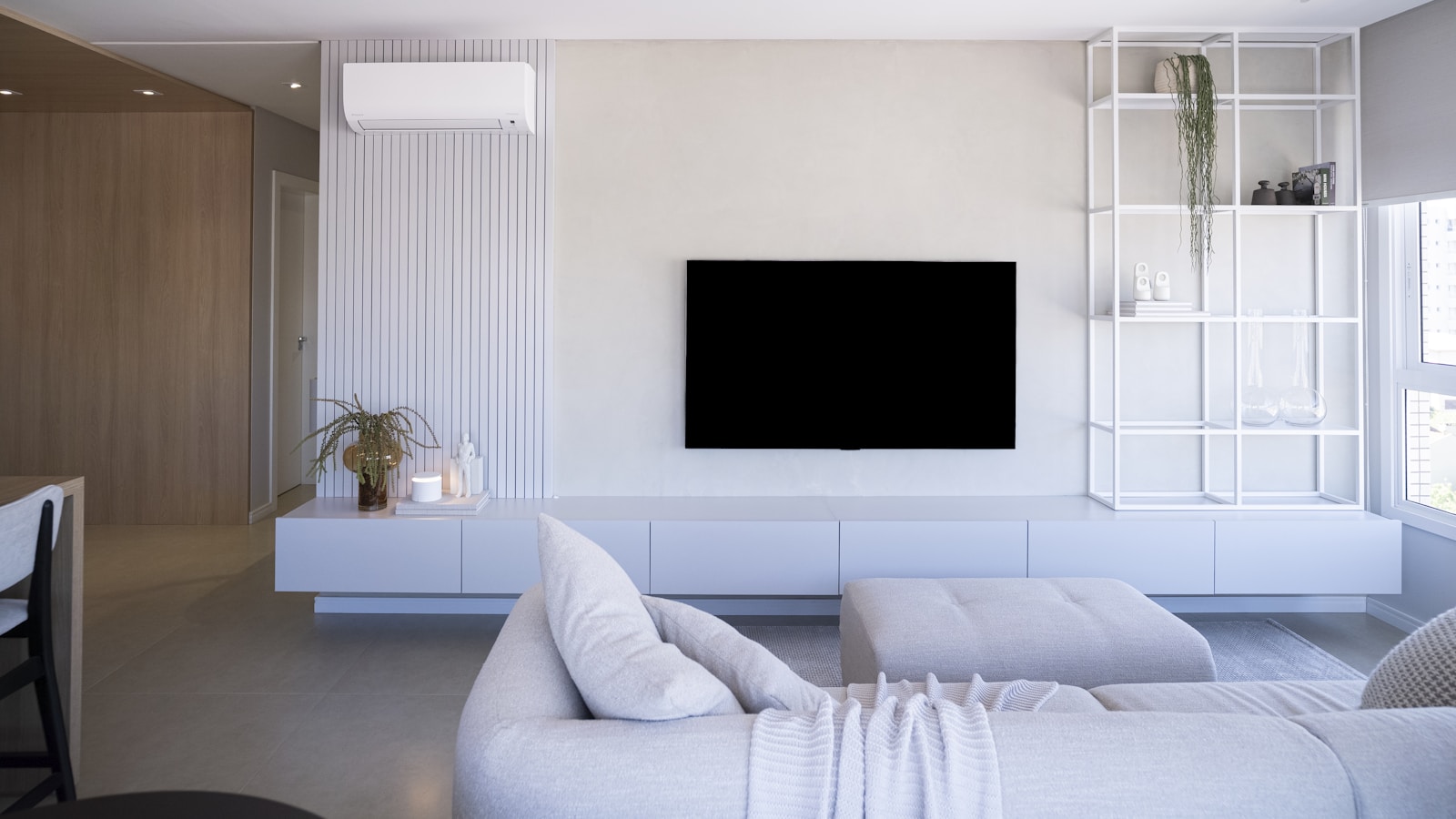 Séjour d'appartement équipé d'une unité murale de climatisation et d'un radiateur électrique